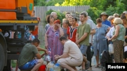 Residents wait in line to collect water delivered by a tank truck in the course of Russia-Ukraine military conflict, in Donetsk, a Russian-controlled city of Ukraine.