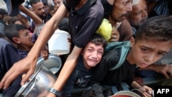 Copiii stau la coadă pentru mâncare la un punct de distribuție din Nuseirat, în centrul Fâșiei Gaza - 11 iunie 2025.