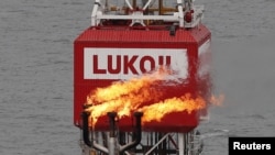O torță de gaz poate fi văzută lângă sigla companiei Lukoil de pe platforma petrolieră Filanovskogo din Marea Caspică - foto arhivă