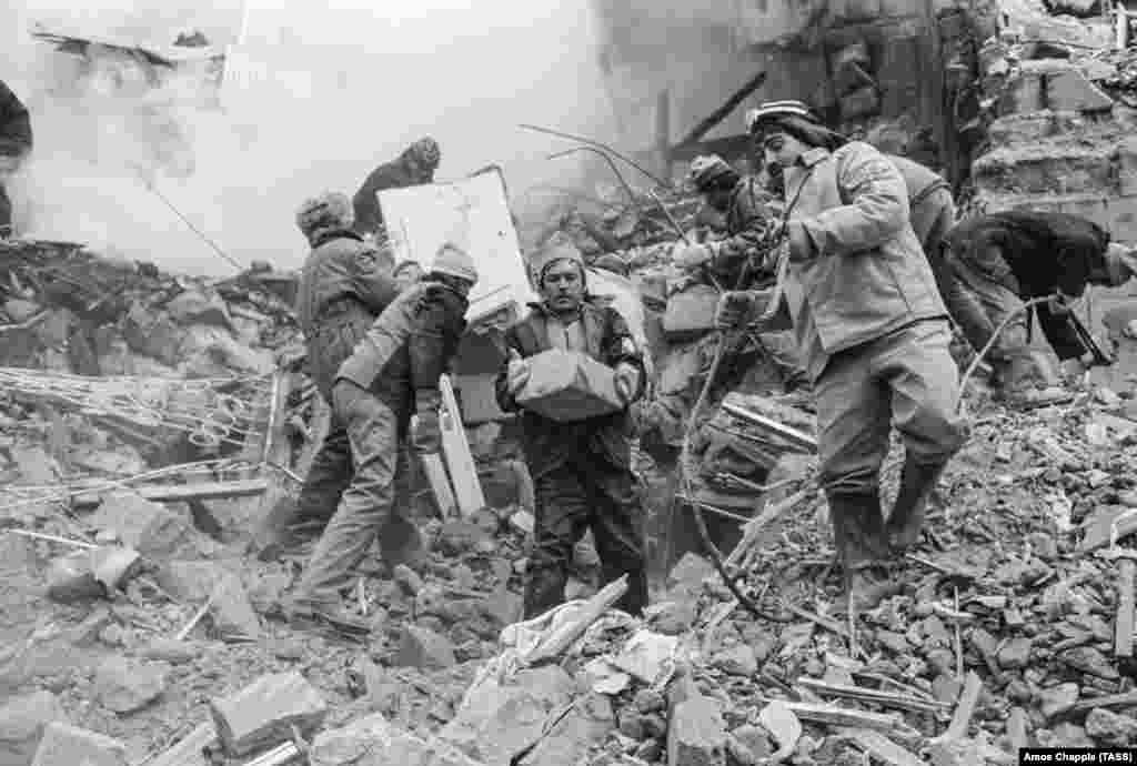 Rescue workers scrambling through broken concrete in Gyumri. Of 78 high-rise apartment blocks in the city, just six survived the quake.