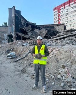 Oleksii Hunyak, de la Universitatea Politehnică de stat din Liov, pozează lângă o grămadă de beton spart, la locul unui atac rus în Ucraina.