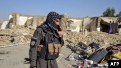 A Taliban security officer stands near a damaged house in Kandahar province on October 16.