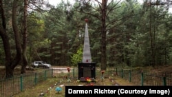 Un obelisc din Novoshepelychi cu inscripția „Aici au fost îngropați oamenii din satele dimprejur care au fost omorâți de invadatorii fasciști în Marele Război Patriotic. 1941-1945”.