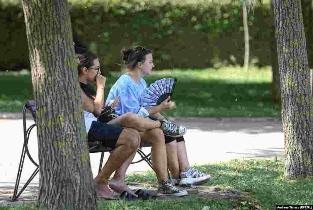 Tineri se răcoresc lângă lacul din Parcul Alexandru Ioan Cuza din București, din cauza temperaturilor ridicate.