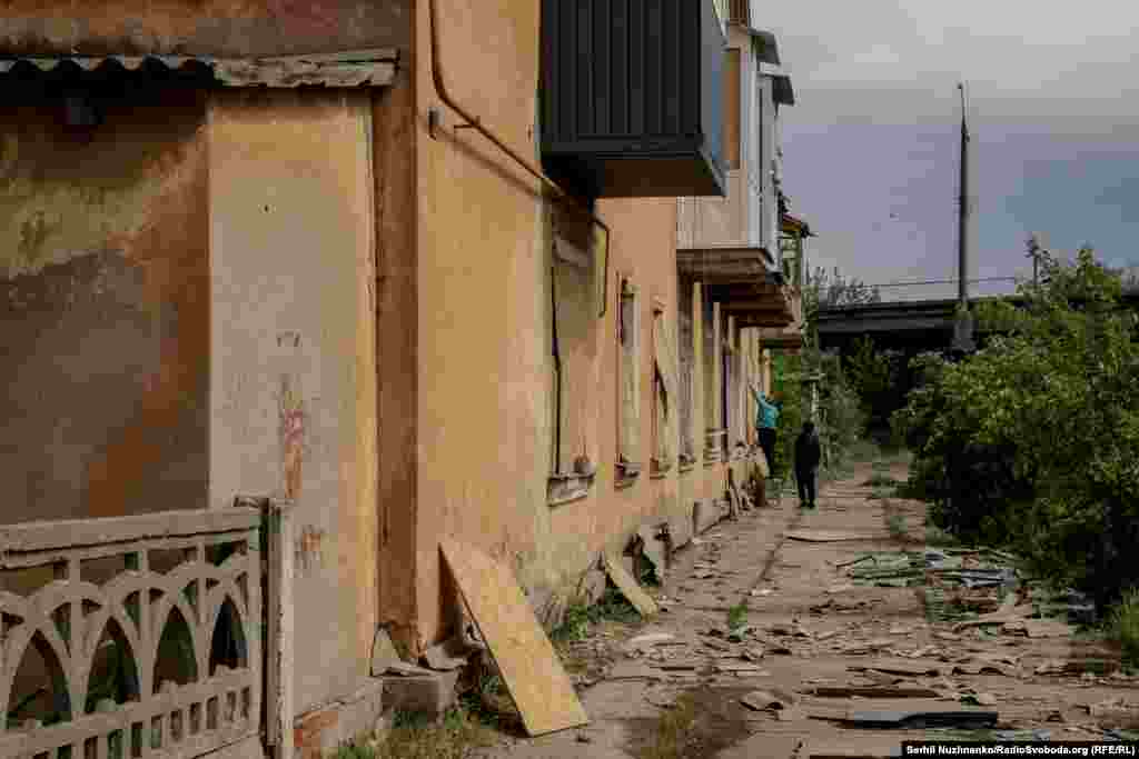 Місцеві жителі забивають вибиті вікна від обстрілів фанерою