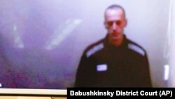 Russian opposition leader Aleksei Navalny is seen on a monitor during a hearing on charges of defamation in a court in Moscow on April 29.