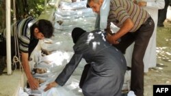 A woman mourns over one of the shrouded bodies of children and other victims that Syrian rebels claim were killed in a toxic gas attack by pro-government forces in eastern Ghouta on August 21.