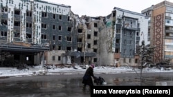 O femeie trece pe lângă o clădire avariată de o rachetă rusească, în orașul Pokrovsk din regiunea Donețk, Ucraina, 12 decembrie 2024