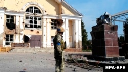 Украинский военнослужащий рядом с разрушенным памятником Ленину на центральной площади в Судже, Курская область, 21 августа 2024 года.