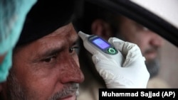 A health official checks the temperature of a government employee in Peshawar on March 12. 