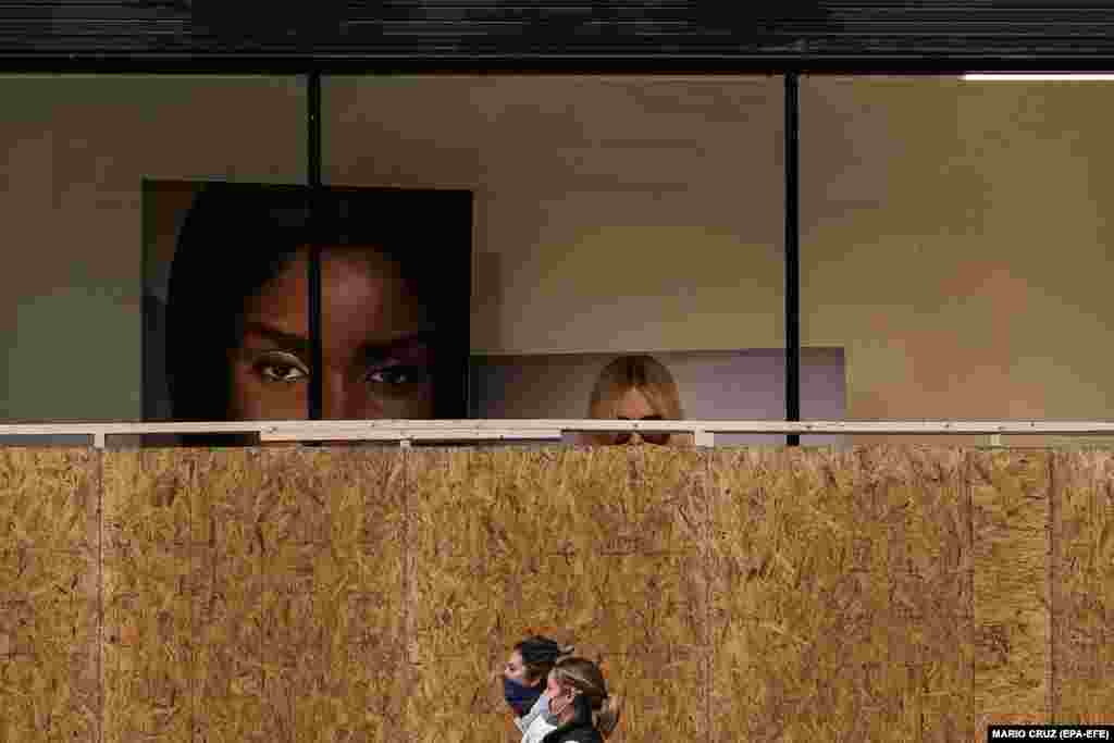 Люди проходять повз крамницю, захищену дерев'яними дошками. Вашингтон, округ Колумбія, США. 1 листопада 2020 року