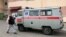 Belarus - April 10. 2020, a town of Dokšycy (Dokshytsy), Viciebskaja voblasc, a patient wearing mask is passing by the local hospital and an emergency car