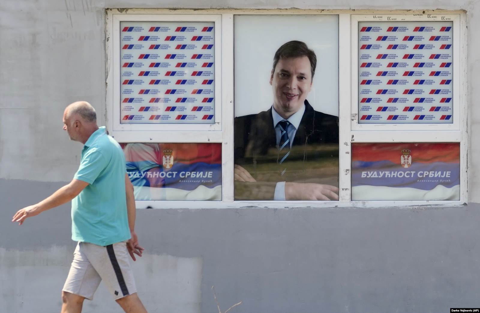 Čovek prolazi pored prozora na kojem se nalazi plakat predsednika Srbije i lidera SNS-a Aleksandra Vučića, 24. juli 2021. 