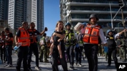 O femeie și copilul ei sunt evacuați de la locul unui atac iranian cu rachetă, în Ramat Gan, Israel. 19 iunie 2025.