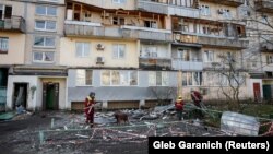 اوکرایني کارکوونکي په کییف کې پر ودانۍ د روسیې ډرون الوتکې د برخو تر پرېوتو وروسته مرستندویه کارونه کوي - د مارچ ۲۳مې انځور. 