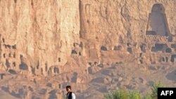 Afghanistan -- A Hazara youth works on a farm in front of the cave-monasteries and the niches where the 174-foot Buddhas, Bamiyan, 25Sep2009