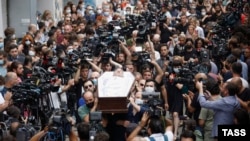 The open coffin of Lekso Lashkarava -- surrounded by mourners and dozens of cameras of fellow TV journalists -- is carried through the streets of Tbilisi on July 13 during his funeral.