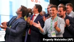 Ukrainian President Volodymyr Zelenskiy (center) applauds with his team as they look at the election results at his party's headquarters in Kyiv on July 21.