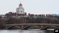Un pod peste râul Charles, care curge prin fața Universității Harvard din Cambridge, văzută în depărtare, 15 aprilie 2025