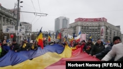 Un steag tricolor uriaș desfășurat de manifestanții împotriva Guvernului Ciolacu