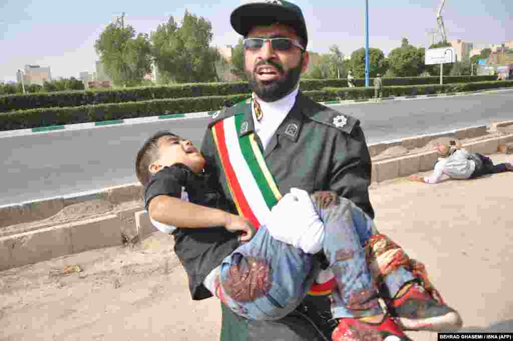 A member of Iran's Islamic Revolutionary Guards Corps (IRGC) carries an injured child.