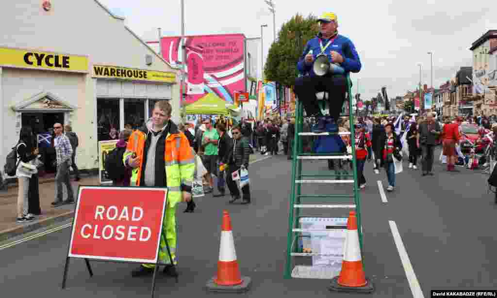 "კინგსჰოლმის" სტადიონისკენ მიმავალ ქომაგებს ასეთი კოშკურებიდან, მეგაფონების გამოყენებით ეხმარებიან ჩემპიონატზე დასაქმებული მოხალისეები.