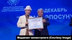 "Жаратман манасчы" сынагынын жеңүүчүсү Асанаалы Калил уулуна Кыргыз Эл артисти, коомдук ишмер, композитор Түгөлбай Казаков сыйлык тапшырган учур. 4-декабрь, 2025-жыл