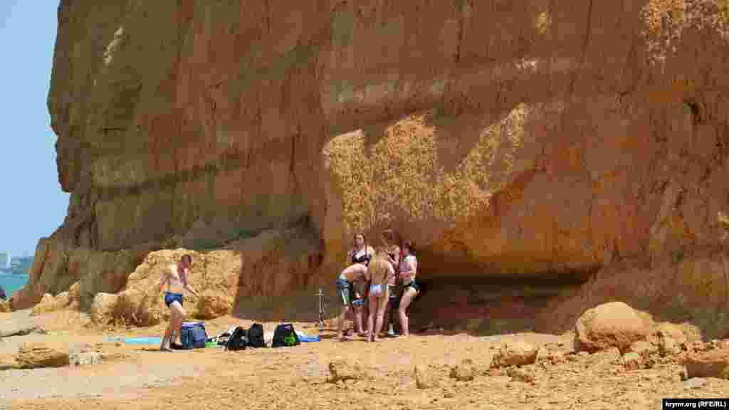 Несмотря на опасность обвала, группа молодых людей расположилась на отдых прямо под обрывом