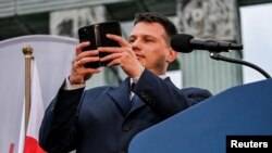 Candidatul ultranaționalist la președinția Poloniei, Slawomir Mentzen, face un video pentru TikTok la un miting electoral pe 10 mai, în apropiere de Monumentul Revoltei din Varșovia.