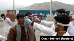 Afghan health workers check the temperature of travelers arriving in the capital Kabul on March 24