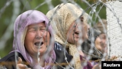 Ethnic Uzbek refugees who have fled from clashes in Osh cry as they gather on the border while waiting for permission to escape to Uzbekistan on June 15, 2010.