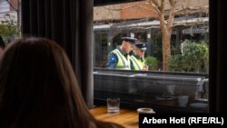 Dy policë duke ecur pranë një kafeneje në Vushtrri.