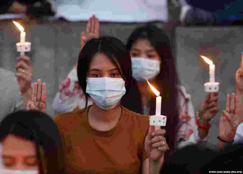 Protestatarii salută cu trei degete și țin în mâini lumânări aprinse în timpul comemorării lui Mya Thwe Thwe Khaing din fața ambasadei SUA. Yangon, Myanmar, 20 februarie 2021. (Foto: Nyein Chan NAING / EPA-EFE )