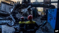 Робітники стоять серед уламків пошкодженої теплоелектростанції ДТЕК після нападу Росії на Україну, 2 травня 2024 року
