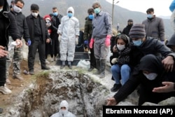 Mourners attend the funeral of a man who died from COVID-19 at a cemetery on the outskirts of the Iranian city of Ghaemshahr on December 16. Officially, the disease has killed more than 56,000 Iranians.