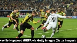 Игроки «Кайрата» (в желто-черном) пытаются остановить форварда «Реала» Мбаппе (в белом). 30 сентября 2025 года