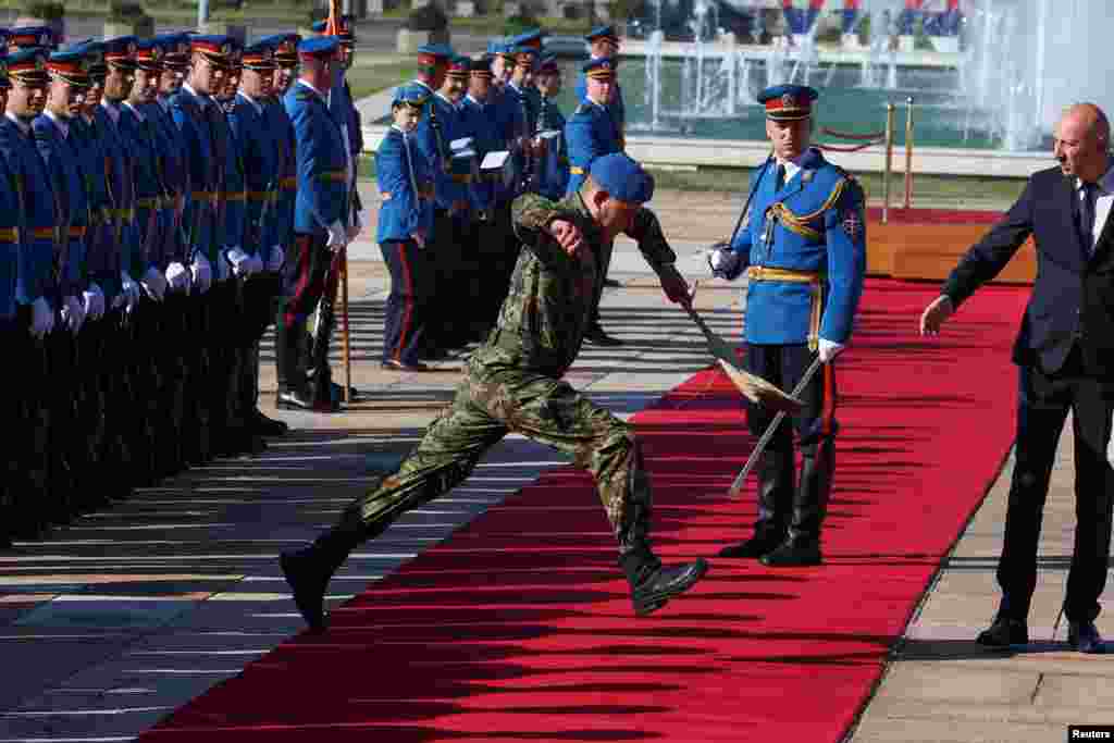 Сербиянын борбор калаасы Белград. Европа Кеңешинин төрагасы Антониу Коштаны тосуп алууга даярдык. Колуна шыпыргы кармаган жоокер кызыл килемди тазалап, даярдап жатышкан учурда сүрөткө тартылып калган.