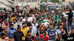 د غزې اوسېدونکي د وژل شویو خبریالانو جسدونه هدیرې ته لېږدوي - د اګست ۱۱مې انځور.