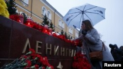 A woman lays flowers for the victims of the St. Petersburg blast by the Kremlin walls in Moscow.
