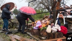 Femei punând flori la ruinele unei case distruse, unde trei copii au fost uciși într-un atac rusesc în regiunea Jitomir din Ucraina.