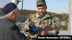 "Достук" бекетиндеги кыргыз чек арачысы бир жарандын документин кароодо. Кара-Суу району, 26-октябрь, 2011.