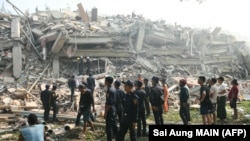 Мьянмадагы жер титирөөдөн улам урап түшкөн имараттын жанында топтолгон жергиликтүү тургундар жана куткаруучулар. 