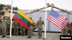 Салдаты трымаюць літоўскі і амэрыканскі сьцягі падчас цырымоніі адкрыцьця амэрыканскага вайсковага лягеру Herkus у Падбродзьдзі, Літва, 30 жніўня 2021 году