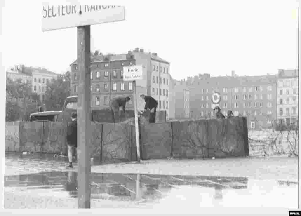East German police patrol a temporary, prefabricated section of the Berlin Wall. - After midnight on August 13, East German troops began erecting what Communist East German leader Walter Ulbricht called an "anti-fascist protection barrier." On June 15 of that year, he had declared: "Nobody intends to build a wall."