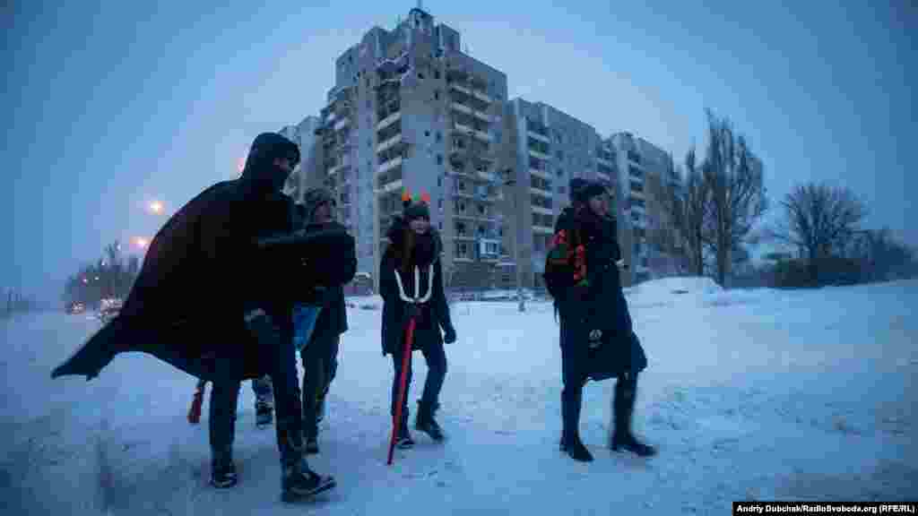Учасники різдвяного вертепу з авдіївського осередка скаутської організації &laquo;Пласт&raquo; йдуть колядувати у стару частину міста повз розбиті боями дев'ятиповерхівки на околиці Авдіївки, 7 січня 2019 року &nbsp;