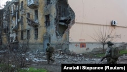 Военнослужащие проходят мимо жилых домов, поврежденных в результате российского удара по Константиновке, Донецкая область, 7 декабря 2025 года