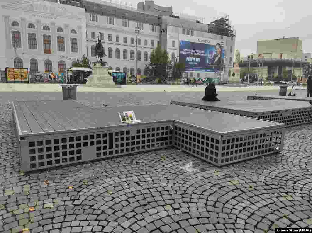 Piața Universității - fără niciun copac, iar din loc în loc sunt hârtii aruncate pe jos.